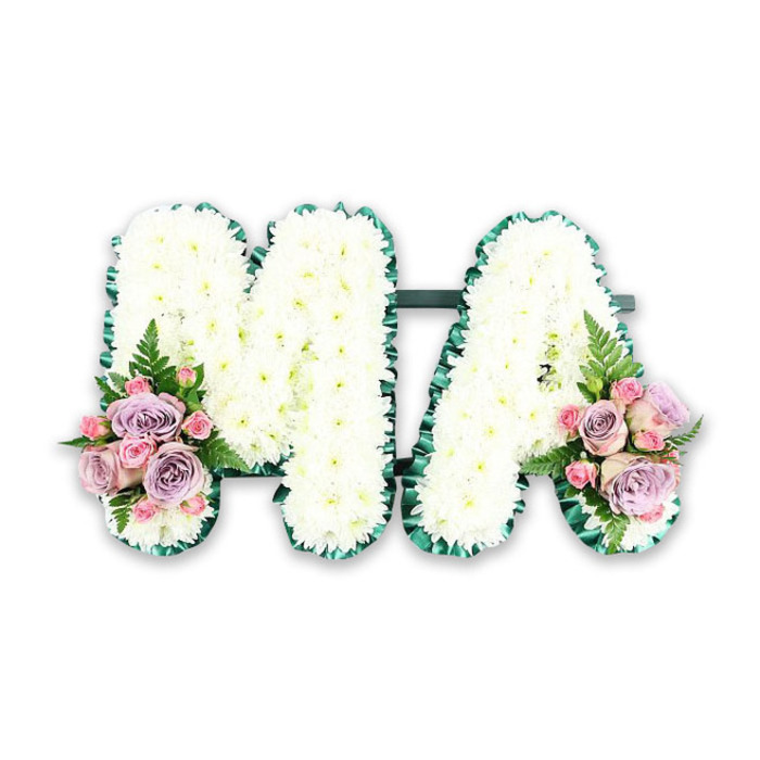 This detailed product-style photograph shows a funeral letter tribute spelling "MA", a design that many families in Lisson Grove might choose when saying goodbye to a beloved mum or "Mama". The two letters stand side by side on a discreet supporting frame, joined by a slender dark green bar that keeps them firmly united while remaining almost invisible beneath the flowers. Every surface of the M and the A is densely packed with pure white chrysanthemums, their small, layered petals overlapping to form a lush, padded texture. The uniformity of the blooms creates an impression of softness and serenity, like a white blanket of blossoms laid carefully in remembrance. Encircling both letters is a deep emerald green ribbon, folded and ruffled into neat pleats that follow each angle and curve. This ribbon edging is smooth and slightly reflective, providing a polished frame that crisply defines the clean lines of the capitals and sets off the white flowers with a strong yet understated contrast. At the base of the left leg of the M and the right leg of the A, two matching floral accents introduce colour and emotional nuance. Gently shaded lilac roses and pale pink roses are grouped together in compact posies, their rounded heads at different stages of opening, from tight bud to fully unfurled rosette. Interspersed between them are clusters of pink spray roses, smaller but equally detailed, adding intimacy and texture. A single fern frond in each cluster extends outward in a graceful arc, its fine leaflets creating a feathery silhouette that softens the geometry of the letters. The neutral white background keeps the focus entirely on the workmanship: the careful placement of every chrysanthemum, the precise ribbon pleating, and the thoughtful choice of soft pastel tones. This MA tribute feels perfectly suited to a memorial service in the Lisson Grove and Marylebone area, where families seek dignified, personalised flowers to express love, respect, and treasured memories.